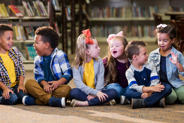 Image of happy children sitting on the floor in a library.