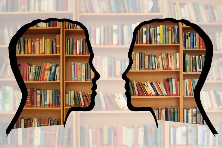 Silhouette of two people in front of book shelves