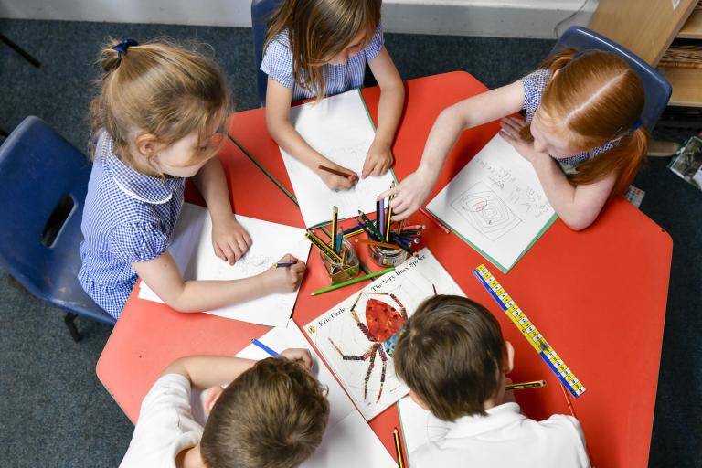 Five children sat round a table writing
