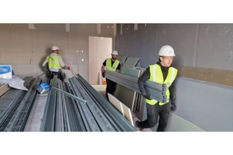 Three adults working on a construction site