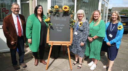 Cllr Martin Harris, Janice Lowery, Alison Glanville and representatives from Hospice at Home stand by welcome board to room opening