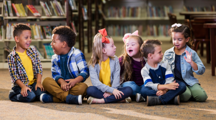 Image of happy children sitting on the floor in a library.