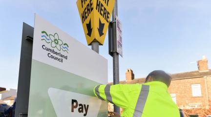 person stood next to a car parking sign