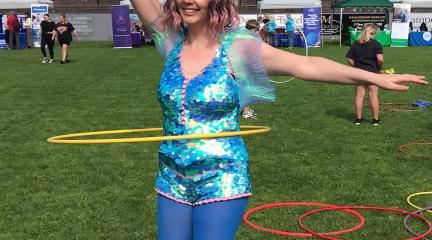 Street entertainment at the 2024 Whitehaven Wellbeing Festival. A woman hula hooping.
