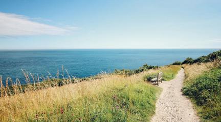 A cliff top path with an empty bench