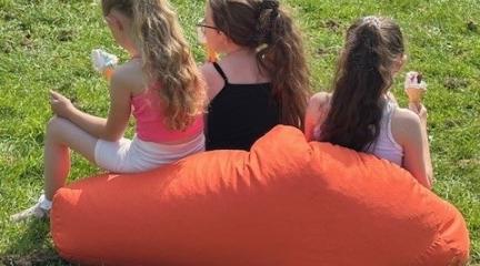 Three girls on an orange bean bag with ice creams. Taken at Operation Respect Northside 2025