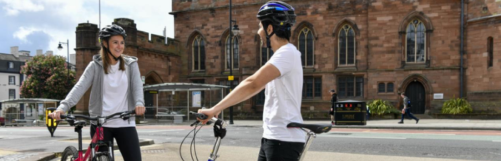 A woman and man standing with bikes in Carlisle City Centre