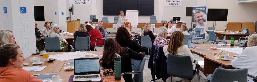People sat in large room listening to speaker