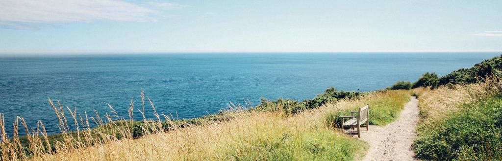 A cliff top path with an empty bench