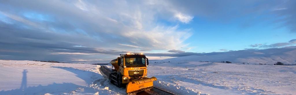 Yellow Gritter in Caldbeck during snowy weather 