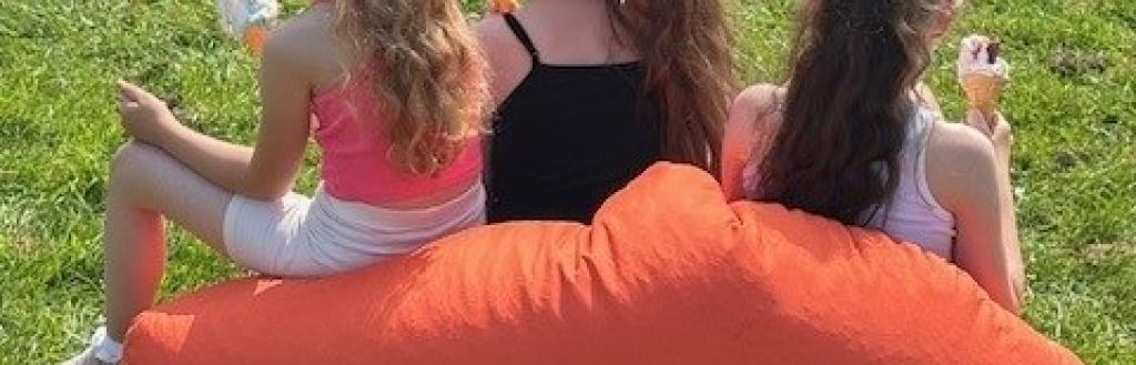 Three girls on an orange bean bag with ice creams. Taken at Operation Respect Northside 2025