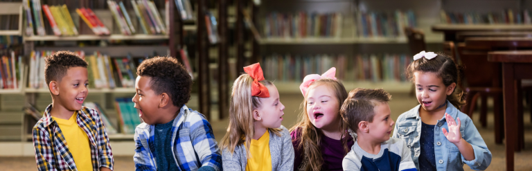 Image of happy children sitting on the floor in a library.